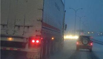 Truck driving with a car on a snowy street