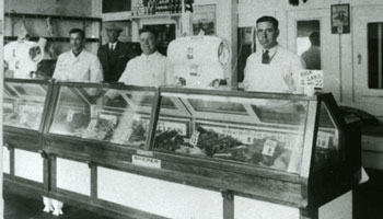 Photo of workers behind meat cooler at the Alberta Meat Market circa 1910-20
