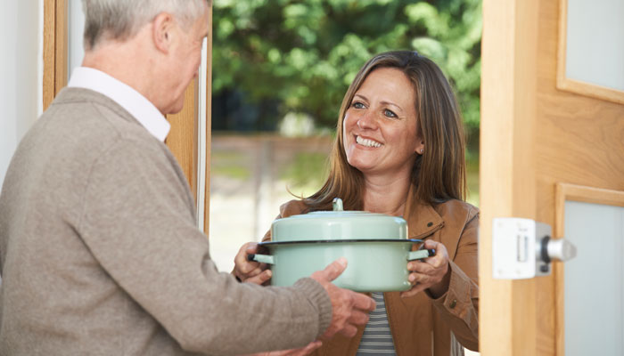 photo of a woman passing a man a casserole dish