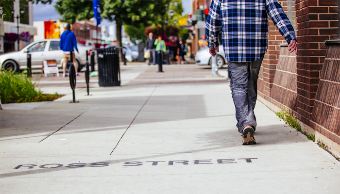 Pedestrian walking along sidewalk towards Ross Street in downtown Red Deer, Alberta