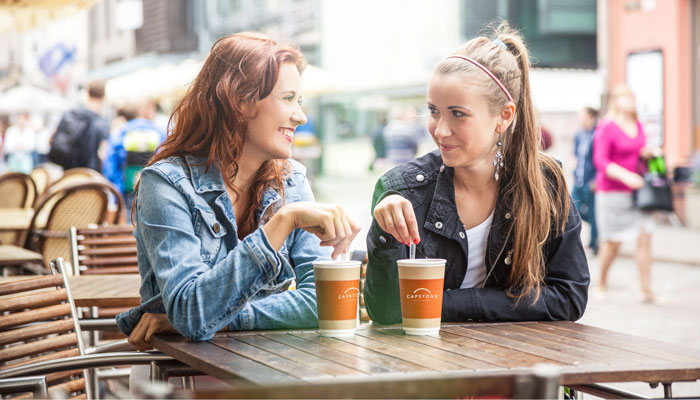 Two women sitting at an outside table enjoying coffees