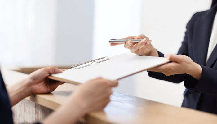 Employee handing over a clipboard and pen to a customer