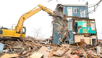 bulldozer demolishing a house with rubble lying everywhere