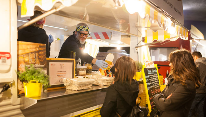 Photo of food truck operator handing customer her order