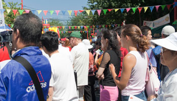 a crowd of people standing on the street with flags draped across the street lights