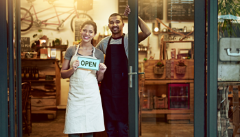 photo of small business owners in front of their store holding an 