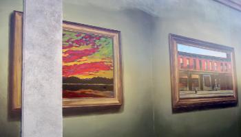 Section of a painted mural of two framed paintings of a landscape and store front.