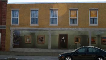 Painted mural on an exterior wall of a building that depicts a store front with apartment windows above.