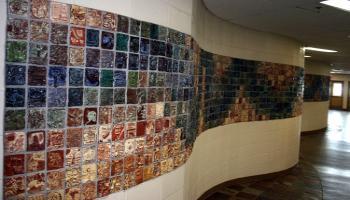 Close up of tiles created by children in various colors, each tile has a different picture. The close up tiles show a football, a child skipping rope and a tipi.