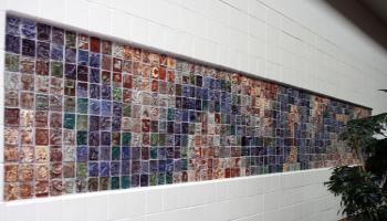 Entire wall filled with square tiles created by children in various colors, each tile has a different picture.