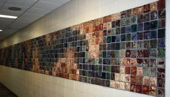 Entire wall filled with square tiles created by children in various colors, each tile has a different picture.