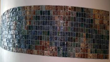 Entire wall filled with square tiles created by children in various colors, each tile has a different picture.
