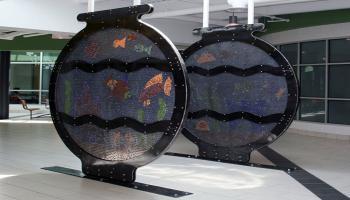 Sculpture of a large round fishbowl with color marbles set to make fish and other aquarium life in the bowl.