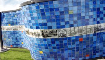 Blue side of a rectangle sculpture made up of glass tiles an the photo etched tiles of old photographs.