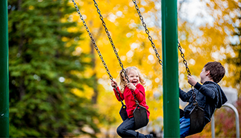 Photo of Little boy and girl on swing