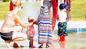 photo of a mom with her 2 kids at the spray park