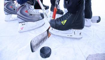 Skates, a puck, and hockey sticks on an outdoor rink